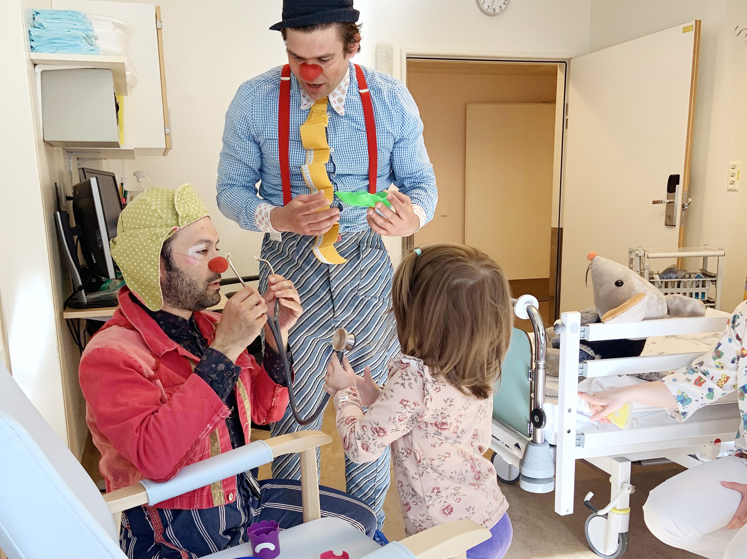 Liten pike holder og leker med stetoskop sammen med to sykehusklovner
